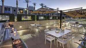 An outdoor dining area with tables and chairs, a grill, and umbrellas. - Sparkling Juhl byFremont-1 queen 1 sofa bed TONS of Amenities (Las Vegas)