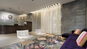A modern lobby with a reception desk, white and purple seating, and a patterned rug. - Sparkling Juhl byFremont-1 queen 1 sofa bed TONS of Amenities (Las Vegas)