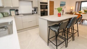 Una cocina moderna con una isla central, taburetes de bar y una zona de comedor con mesa y sillas.