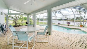 En overdækket terrasse med pool, udendørs møbler og udsigt over det omkringliggende landskab.