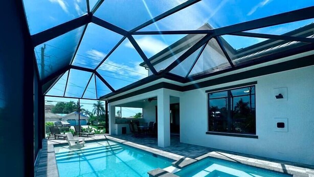 Une maison moderne dotée d’une grande piscine intérieure à panneaux de verre et d’un espace patio.