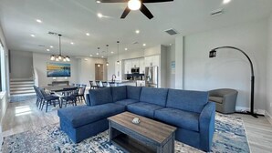 Un salon moderne avec un canapé d’angle, une table basse et un coin repas avec des chaises.