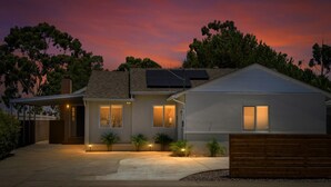 Une maison moderne à deux étages, dotée d’une allée couverte, de panneaux solaires et d’une entrée bien éclairée.