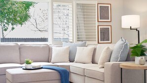 Un salon moderne avec un canapé d’angle, une table d’appoint et une lampe.