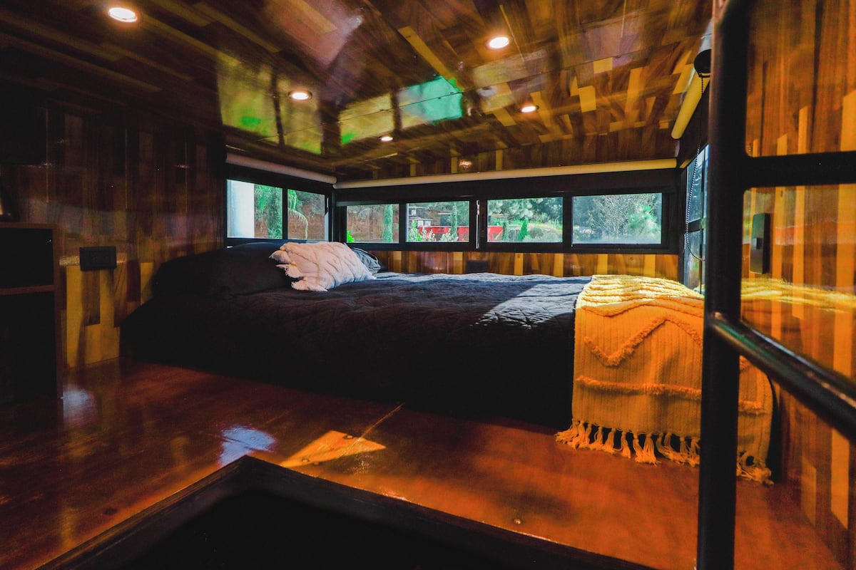 A bedroom with a bed, a window, and a wooden ceiling.