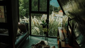 A room with a large window, a sofa, a wooden table, and a potted plant. - K NAJ Community (Omitlán de Juárez)
