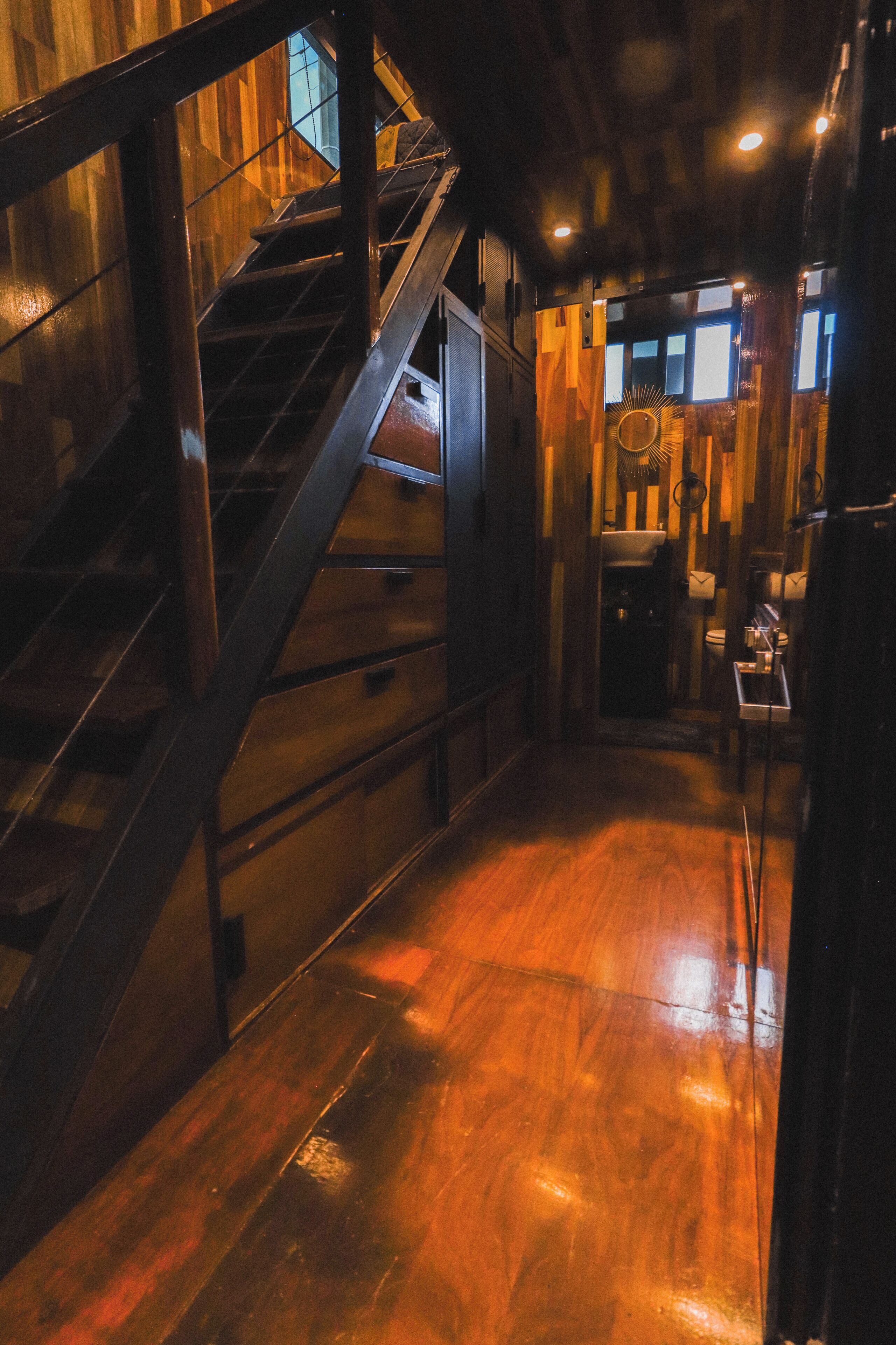 A narrow hallway with wooden flooring and a metal staircase.