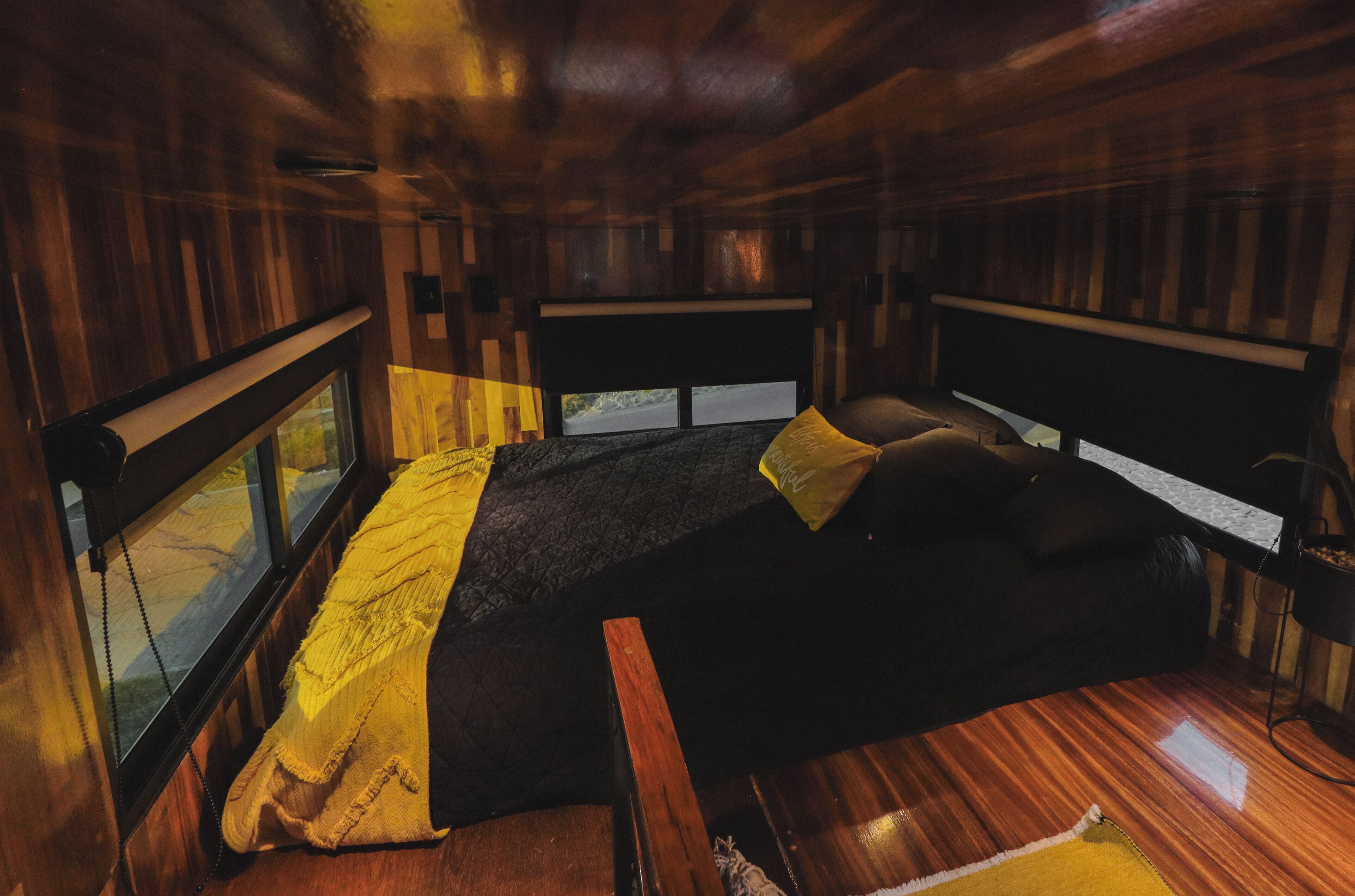 A room with a bed, a window, and a wooden ceiling.
