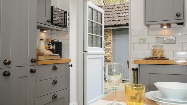 Una cocina con armarios grises, encimera de madera y vistas al exterior.