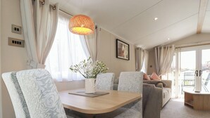Ein modernes Wohnzimmer mit einem Holzesstisch, gemusterten Stühlen, einer Couch und einer Pendelleuchte.