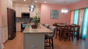 Una cocina moderna con una isla central, una mesa de comedor de madera y sillas.