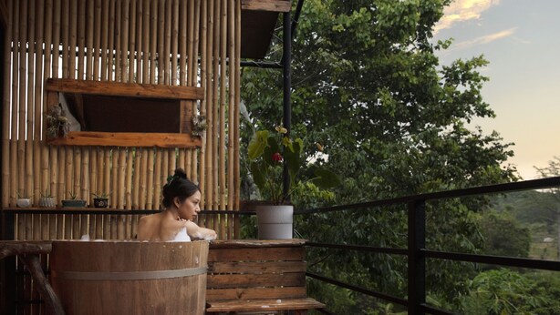 A wooden bathtub on a balcony with a bamboo wall and potted plants. - NUYU Khaoyai (Pak Chong)