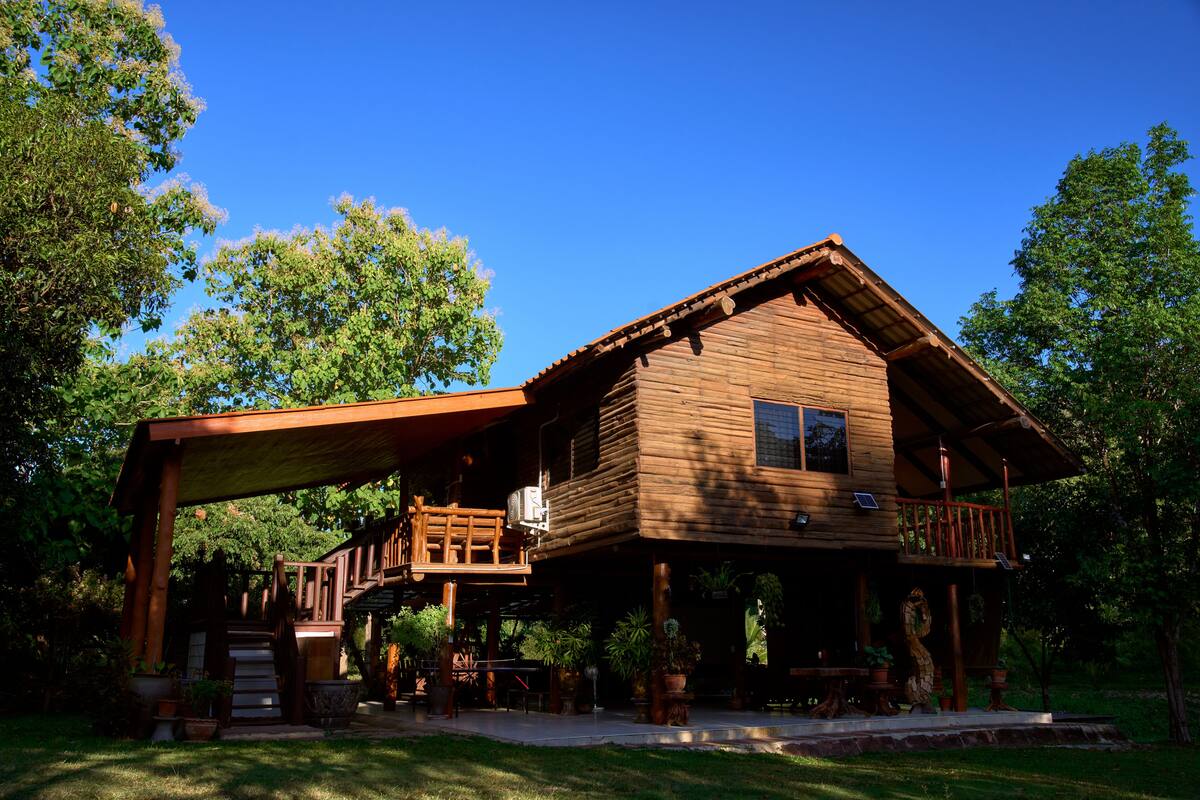 A wooden cabin with a balcony, surrounded by trees.