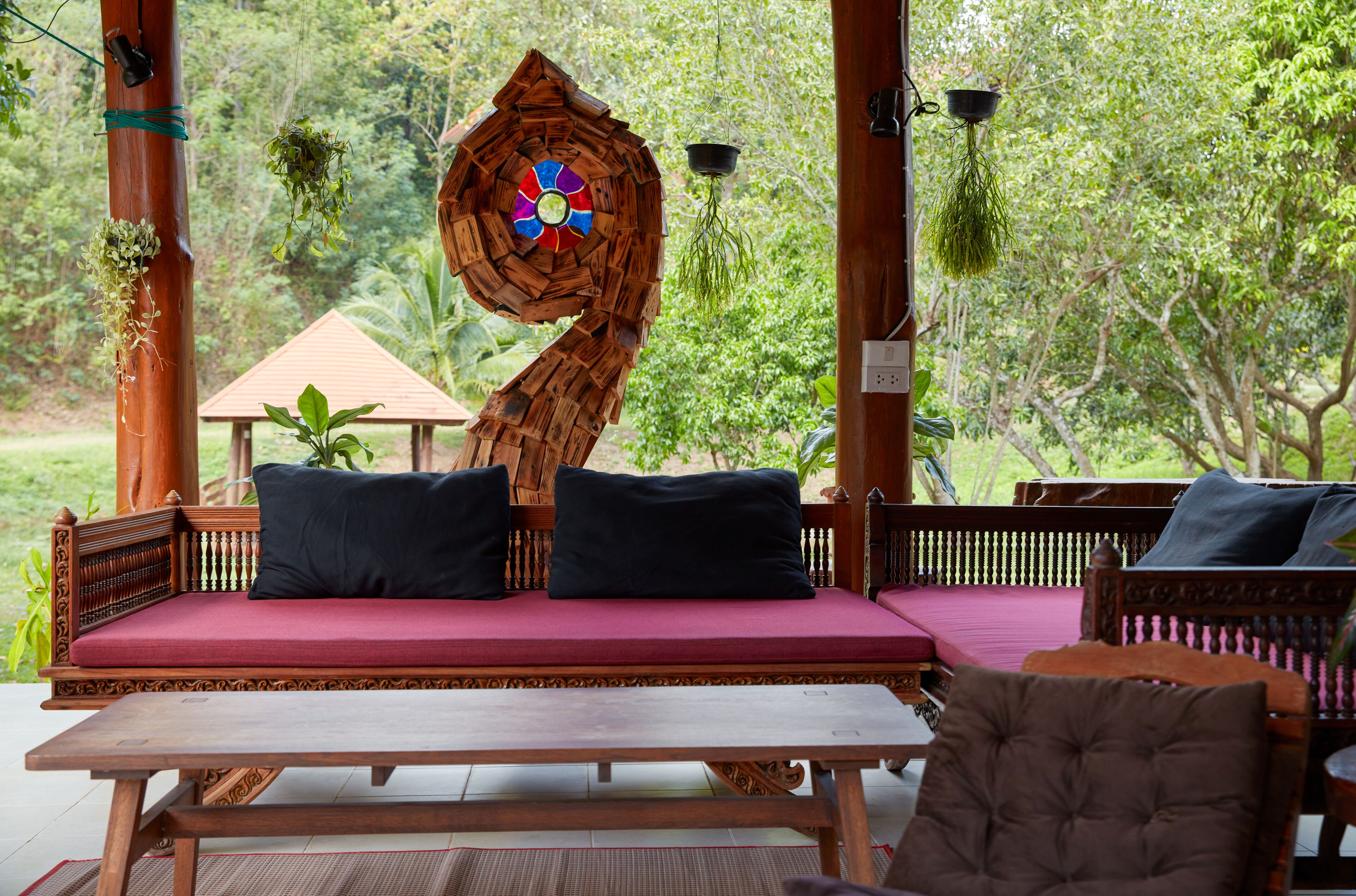 A wooden bench with a red cushion, a wooden table, and a decorative wooden spiral structure.