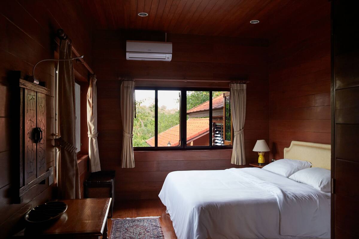 A wooden room with a bed, a window, and a table.