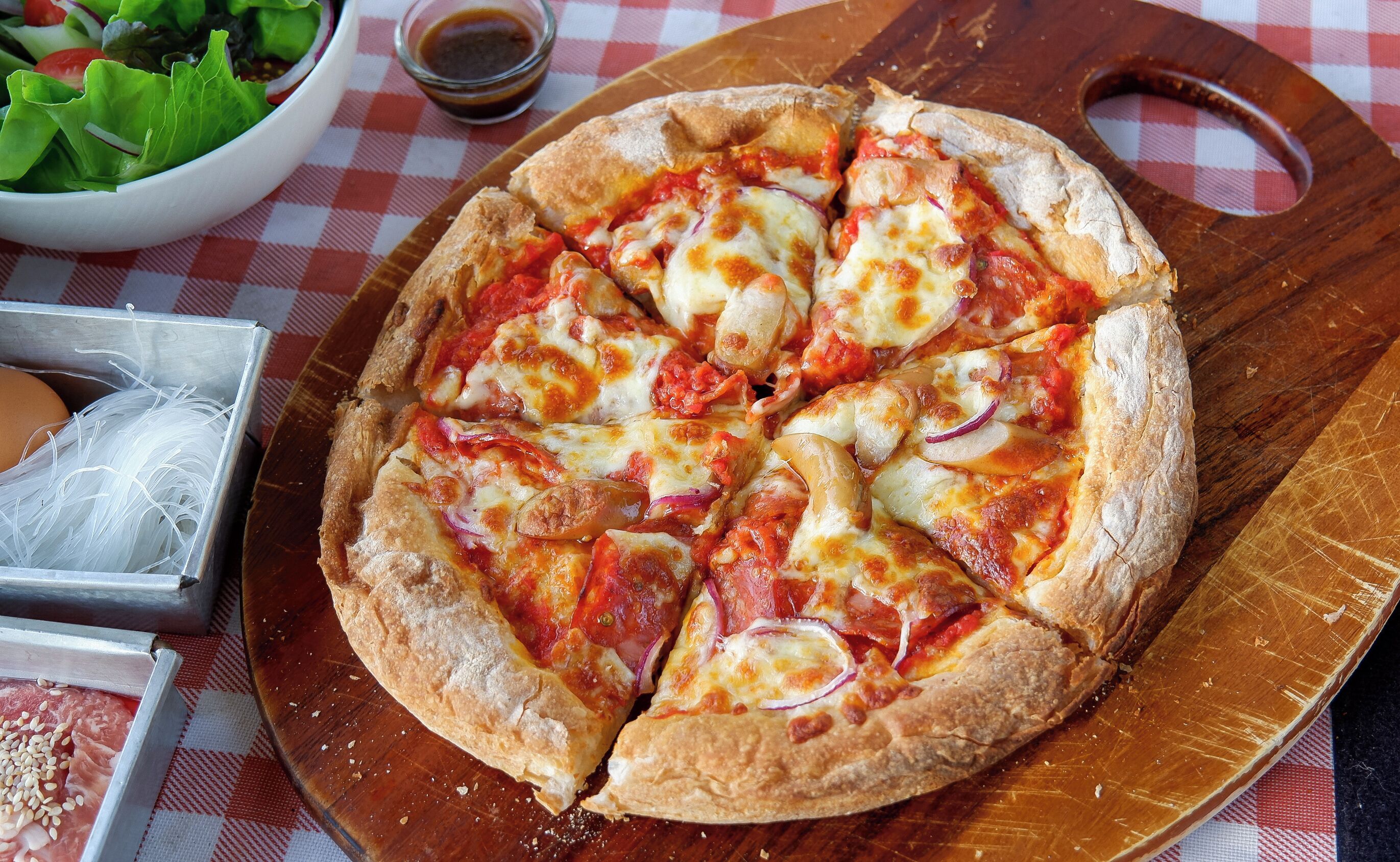 A pizza with toppings on a wooden board.