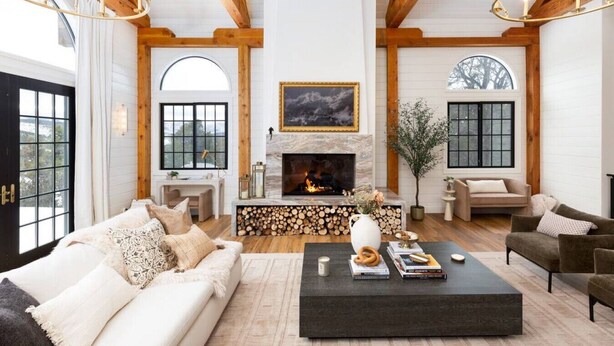 A spacious living room with a fireplace, wooden beams, and large windows. - Aspen Valley Sky Ranch (Carbondale)