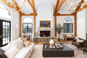 Un salón amplio con chimenea, vigas de madera y ventanas grandes.
