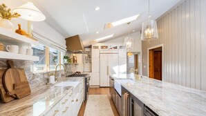 A modern kitchen with white cabinetry, marble countertops, and stainless steel appliances. - Aspen Valley Sky Ranch (Carbondale)