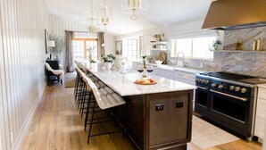 A modern kitchen with a large island, bar stools, a built-in oven, and a marble countertop. - Aspen Valley Sky Ranch (Carbondale)