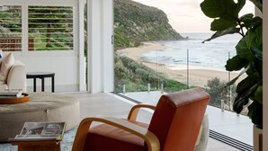 Un saló modern amb una finestra gran que dona a una platja i a l'oceà.