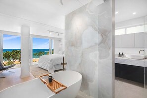 Enjoy a serene ocean view from this spacious room, featuring a large bathtub and sleek accent wall.