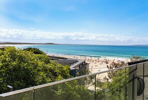 A beach view from a balcony with a clear sky, a sandy beach, and a calm sea. - 71 Hastings Street - Beachfront (Noosa Heads)