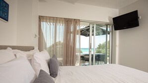 A hotel room with a bed, a TV, and a view of the outdoors. - 71 Hastings Street - Beachfront (Noosa Heads)