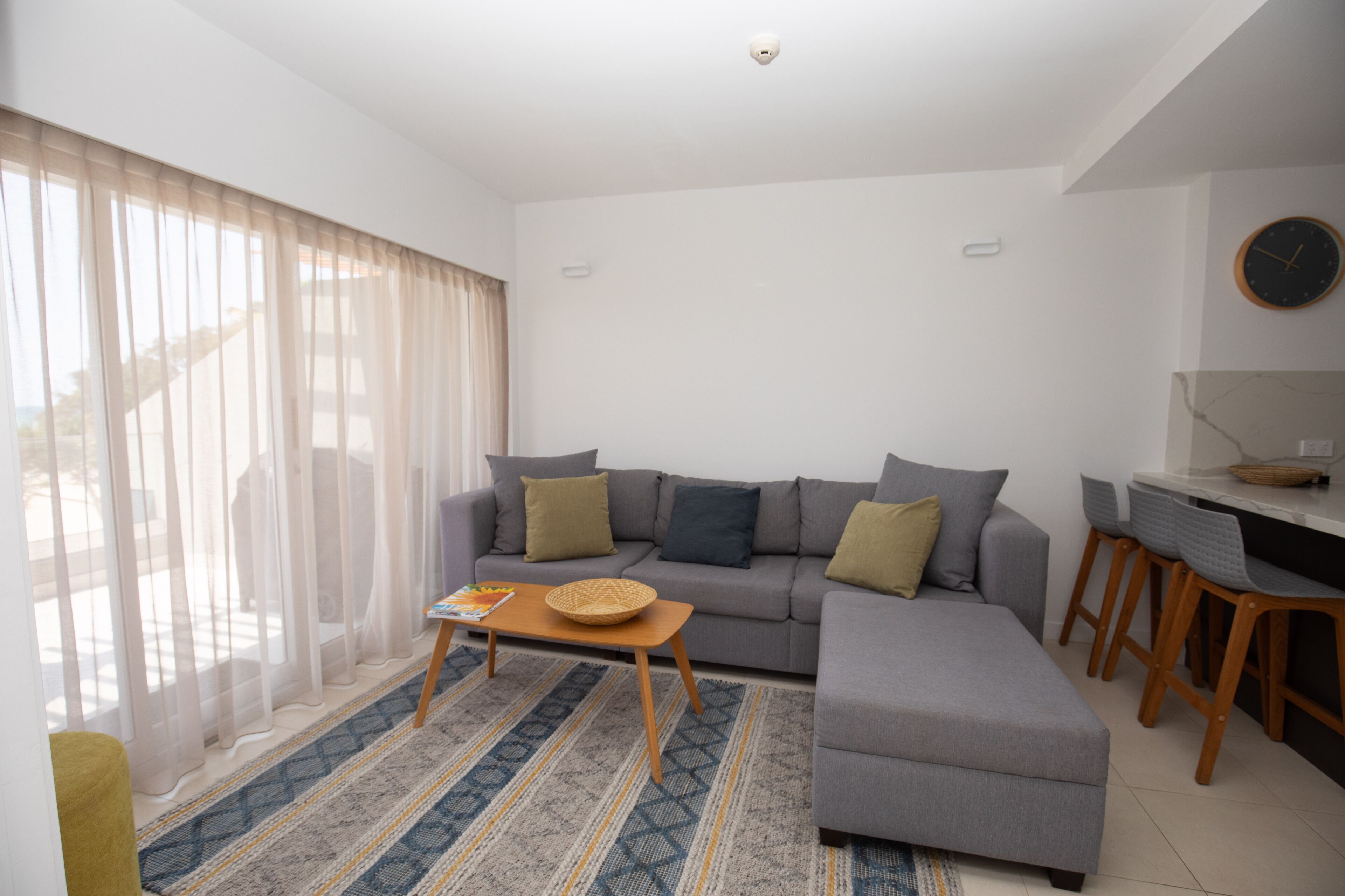 Una sala de estar moderna con un sofá gris, una mesa de centro de madera y un tapete estampado.