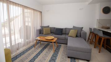 Una sala de estar moderna con un sofá gris, una mesa de centro de madera y un tapete estampado.