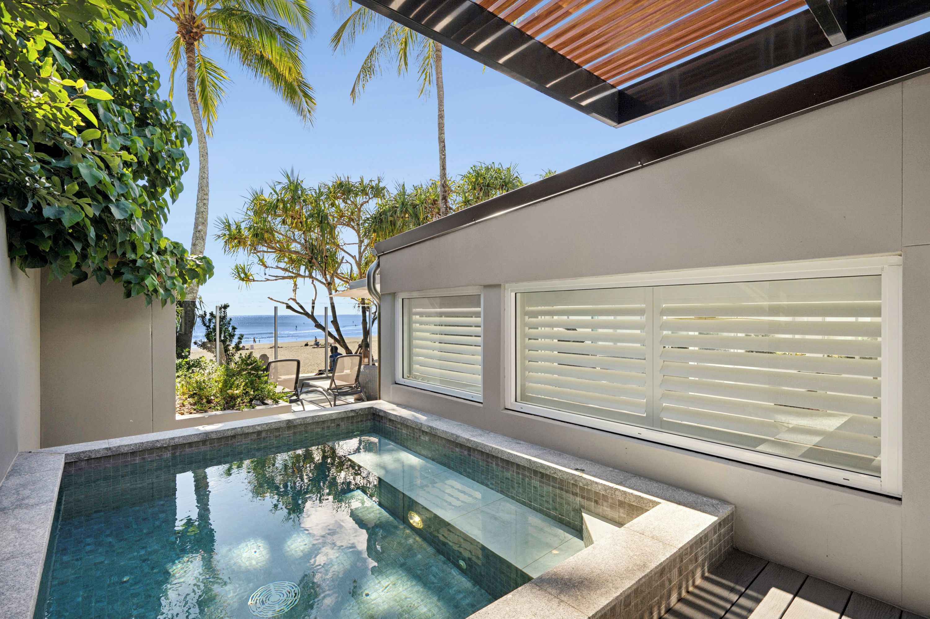 Ein moderner Poolbereich im Freien mit Blick auf Strand und Meer.