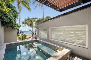 Uma área de piscina moderna ao ar livre, com vista para a praia e oceano.