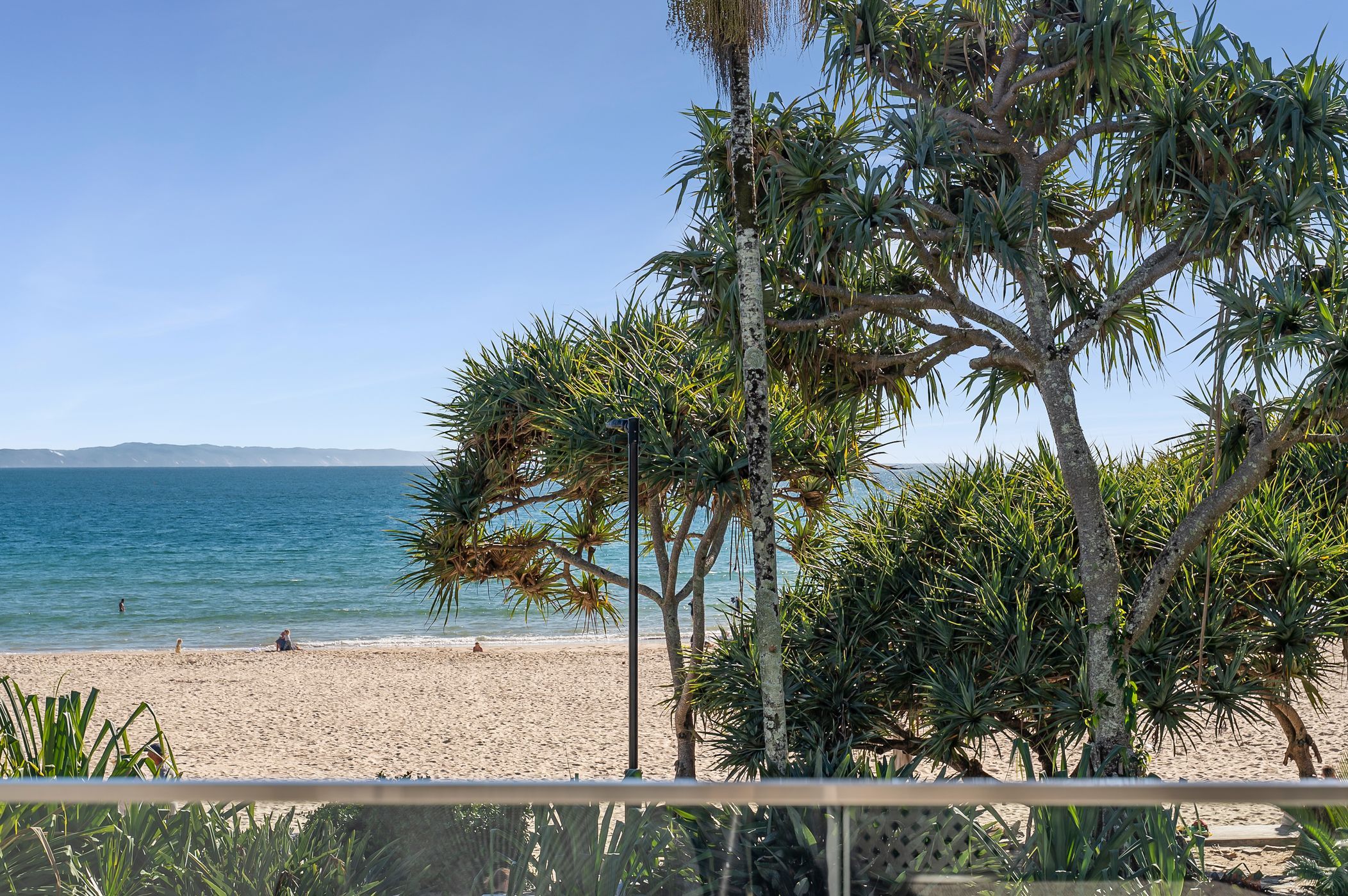 A beach with a clear view of the ocean and distant mountains.