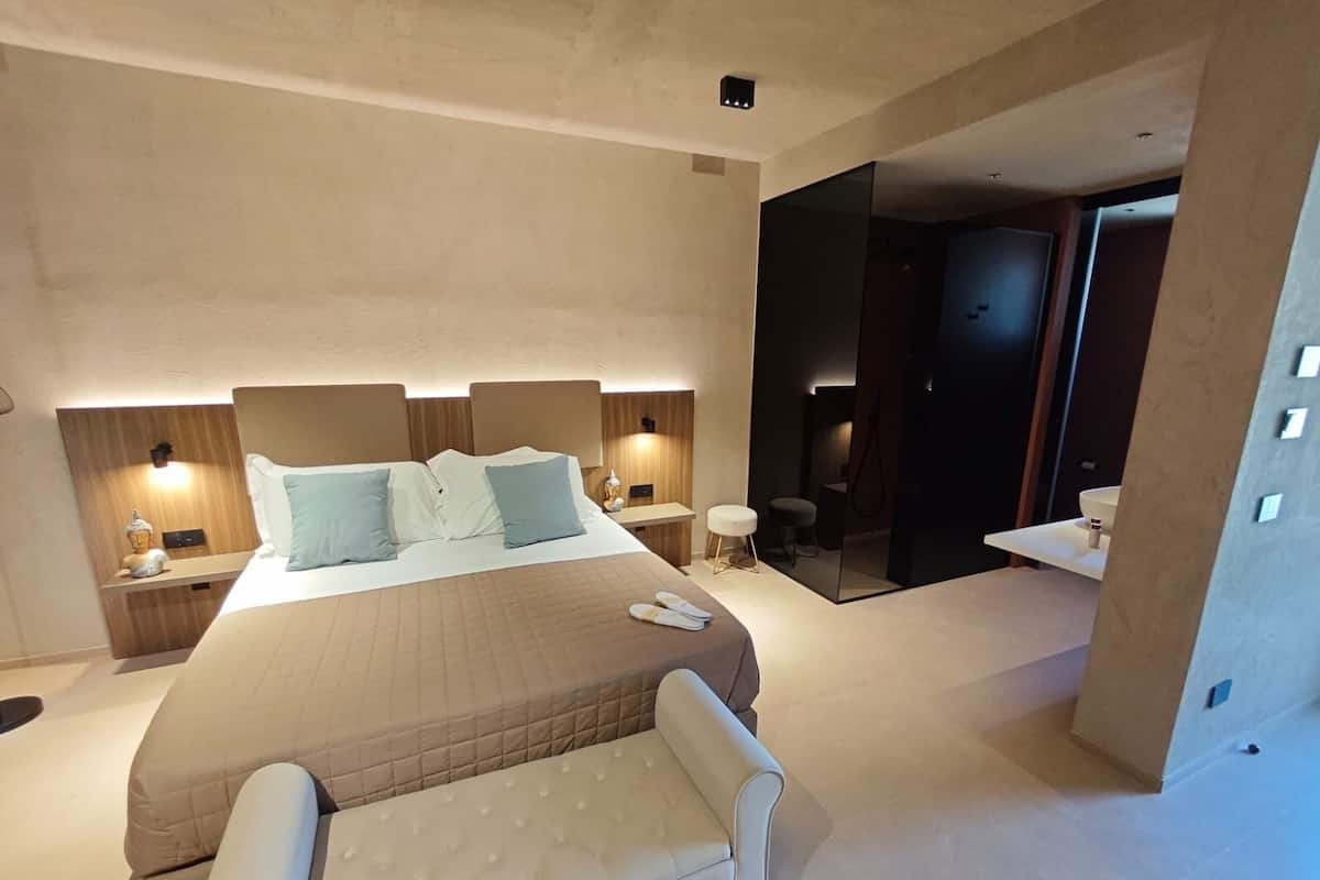 Ein modernes Hotelzimmer mit einem großen Bett, Nachttischen, einer Sitzecke und einem separaten Badezimmer.