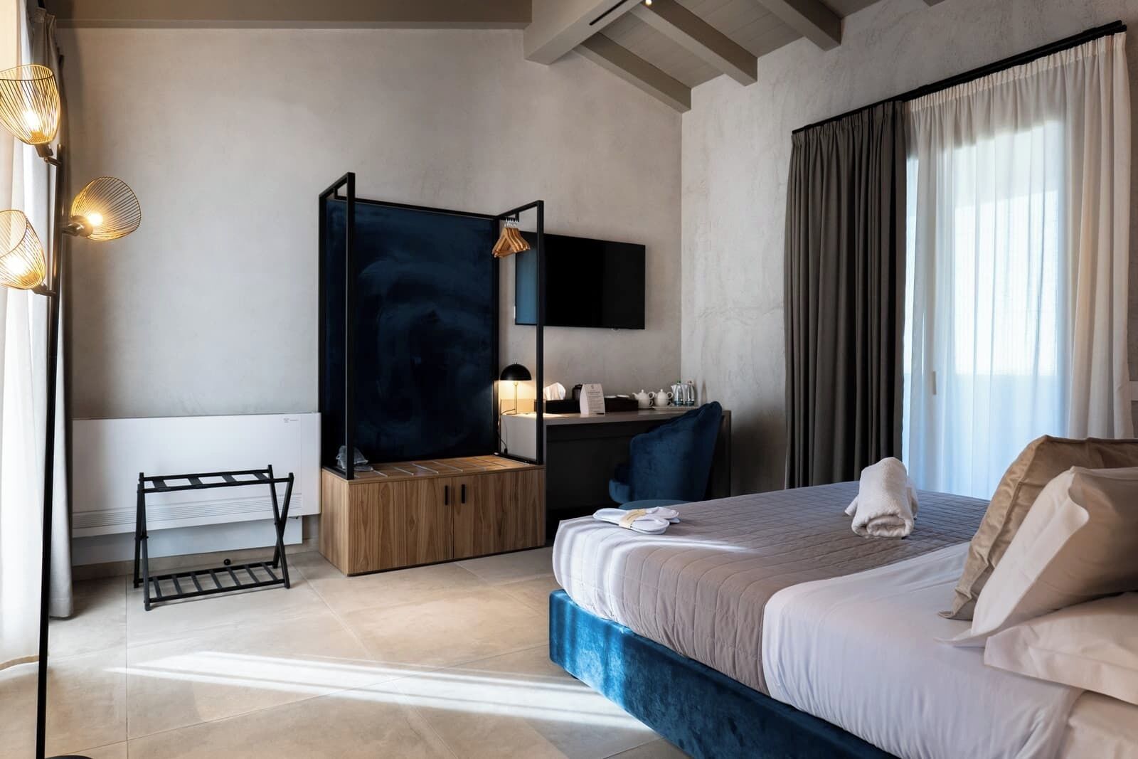 Una habitación de hotel moderna con una cama grande, un escritorio, una silla, un televisor y vistas al exterior.