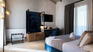 Una habitación de hotel moderna con una cama grande, un escritorio, una silla, un televisor y vistas al exterior.