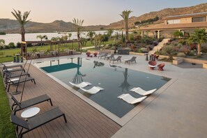 Zona de piscina con sillones de descanso, una pérgola y vistas a la montaña.