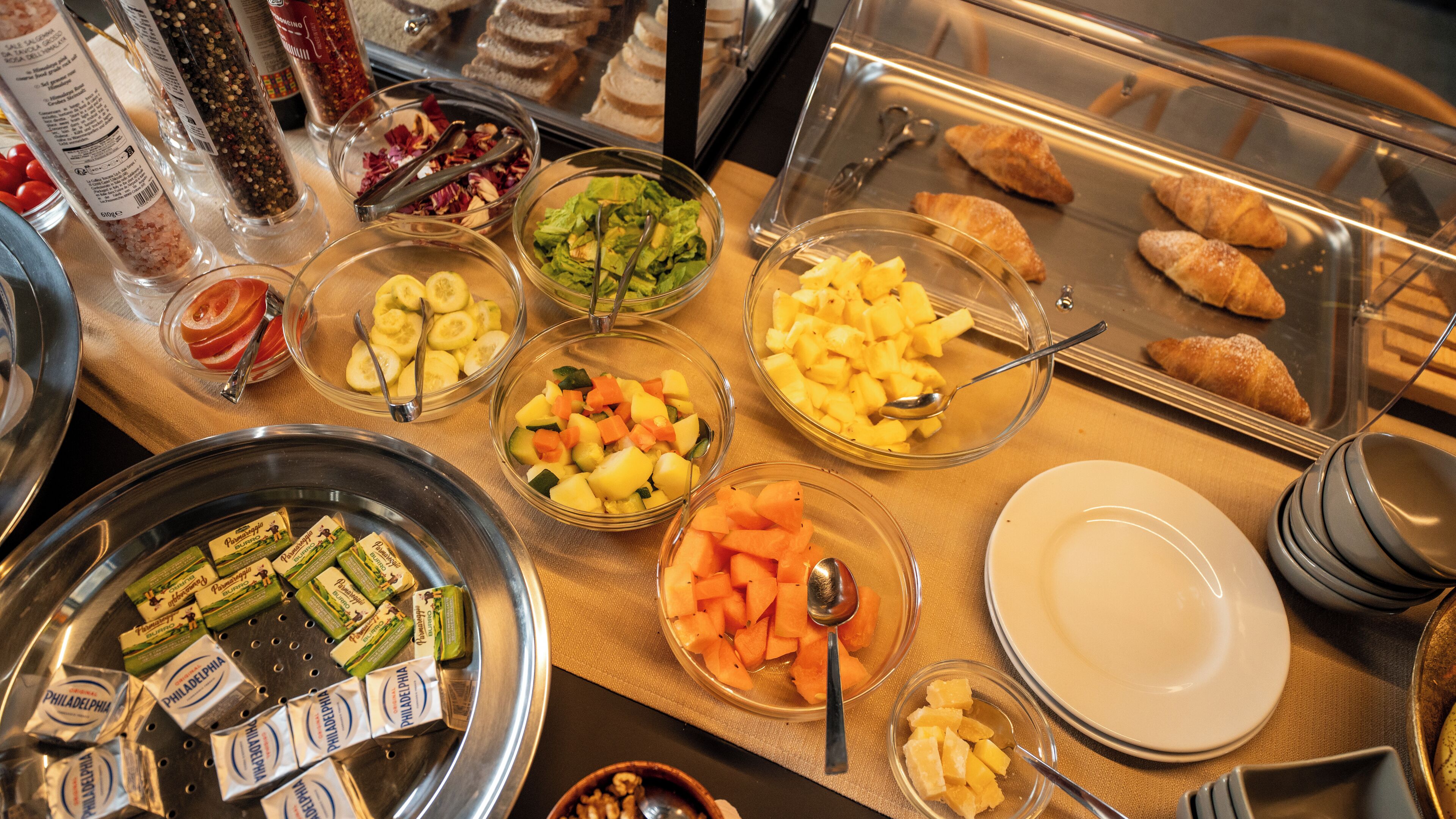 A buffet with various food items including fruits, vegetables, and pastries.