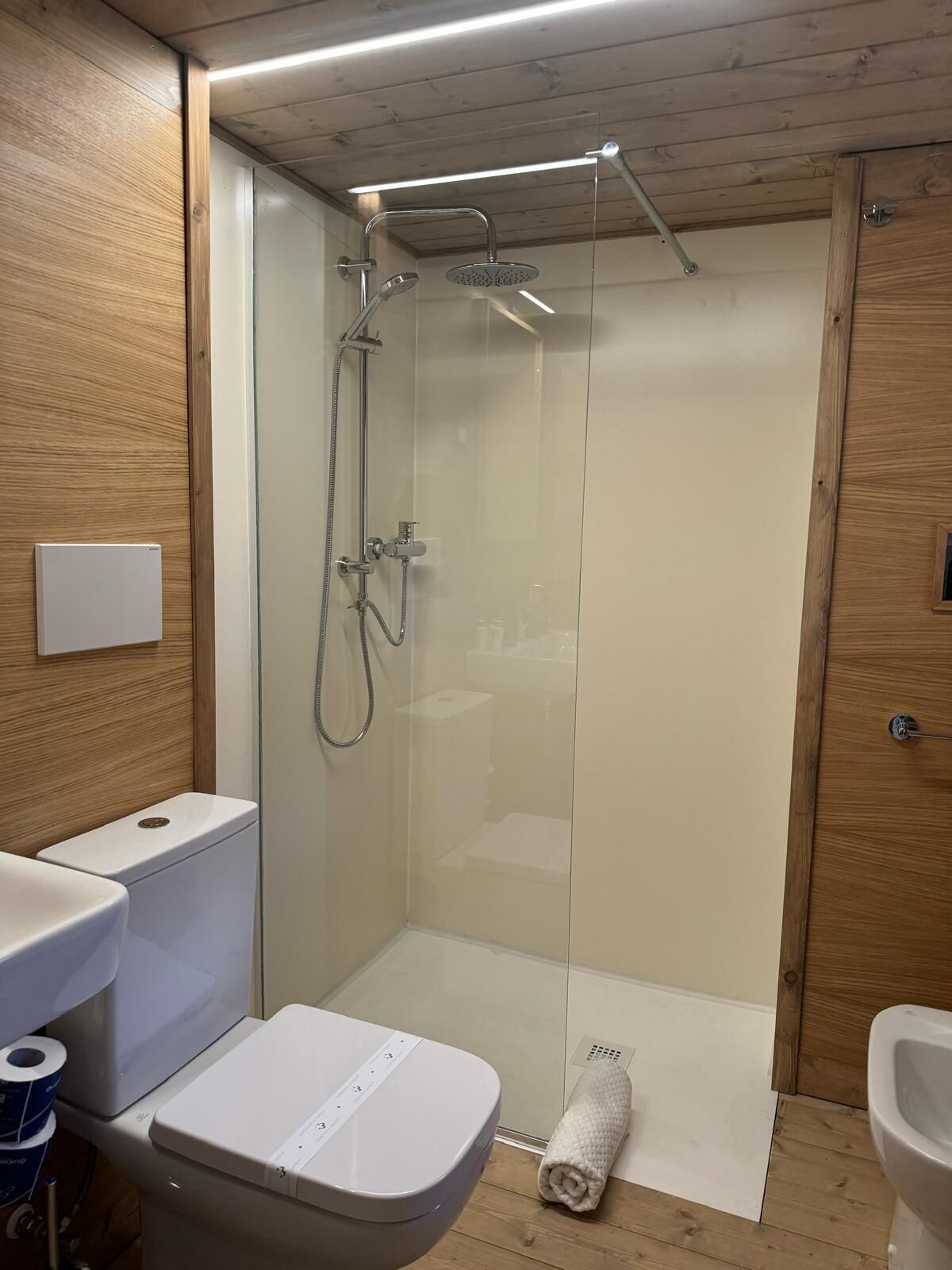 Un baño moderno con ducha de vidrio, inodoro y bidé.