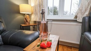 A cozy living room with a leather sofa, a small wooden table with a bottle of Freixenet Italian Rosé, two strawberries, and a glass. - The Beach Retreat (Filey)