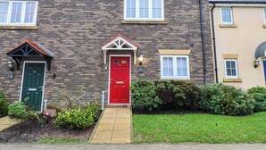 A two-story stone house with a red door, a small porch, and a brick facade. - The Beach Retreat (Filey)