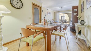 A dining area with a wooden table, chairs, and a clock on the wall.