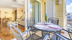 A dining area with a round table set for two, a sofa, and a glass partition.