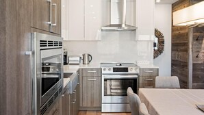 Una cocina moderna con electrodomésticos de acero inoxidable, armarios de madera y un comedor con mesa y sillas.