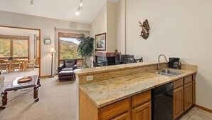 A spacious kitchen with granite countertops, wooden cabinets, and a built-in dishwasher. - Chamonix 37 | Snowmass Ski-In/Ski-Out Condo w/Shared Hot Tub & Pool/Private Washer/Dryer/WiFi (Snowmass Village)