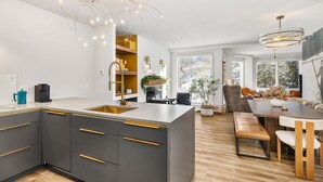 Eine moderne Küche mit einer großen Kochinsel, integrierten Geräten und einem Essbereich mit Holztisch und Stühlen.