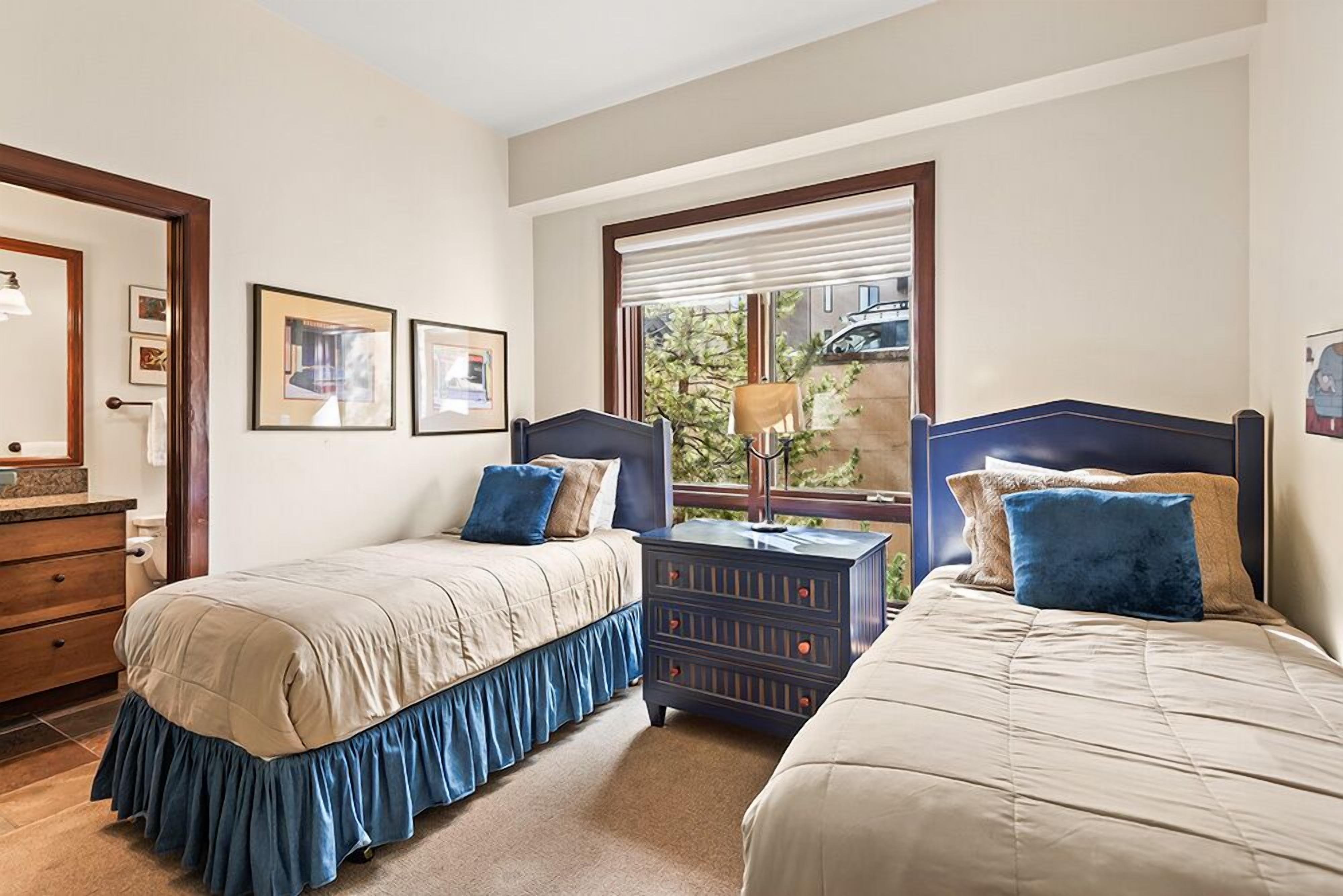 Un dormitorio con dos camas, un aparador y una ventana con persianas.