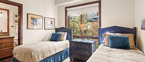 Un dormitorio con dos camas, un aparador y una ventana con persianas.