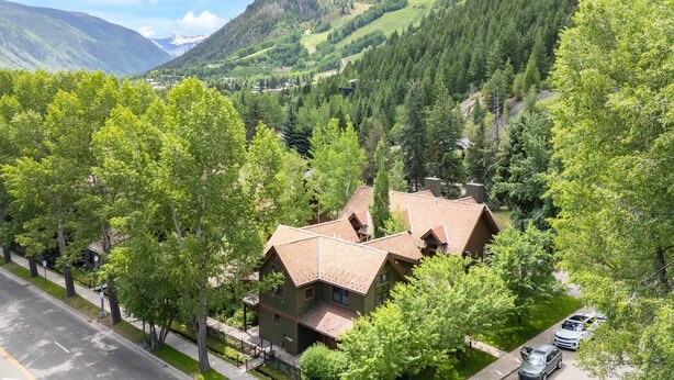 A house with a sloped roof, surrounded by trees and a mountain backdrop. - Christiana Lodge 102A | Studio in Aspen with Hot Tub access (Aspen)