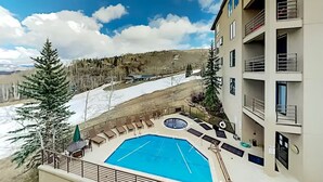 A hotel with a pool area, outdoor seating, and a view of a snowy landscape. - Chamonix 54 | Snowmass Ski-In/Ski-Out Condo with Pool, Hot Tub, Free WiFi, & Airport Shuttle (Snowmass Village)
